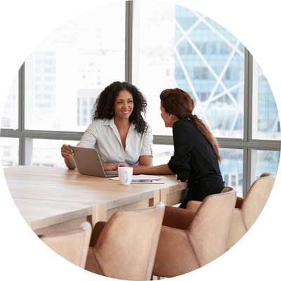 Two women talking at a board room table.