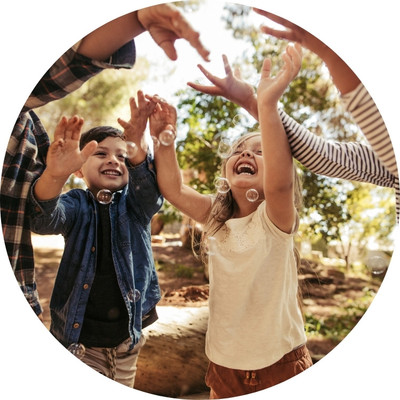 A group of kids playing with bubbles in a park.