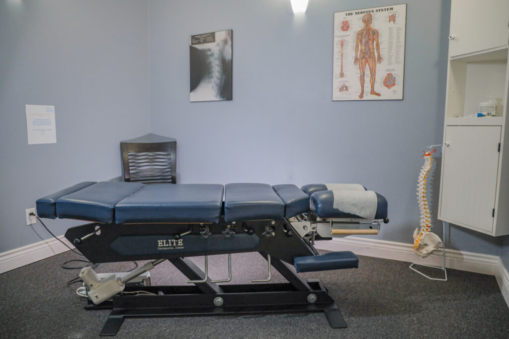 A view of a chiropractic care room with treatment table and spine model